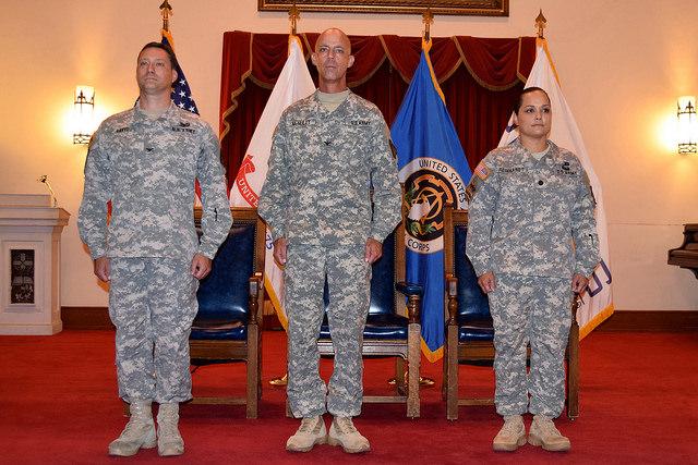 Three soldiers stand on stage in front of crowd.