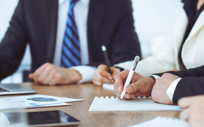 People in a boardroom planning on pen and paper.